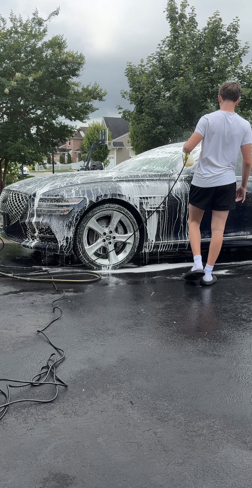 The NorWash team hand-washing a luxury sedan with foam